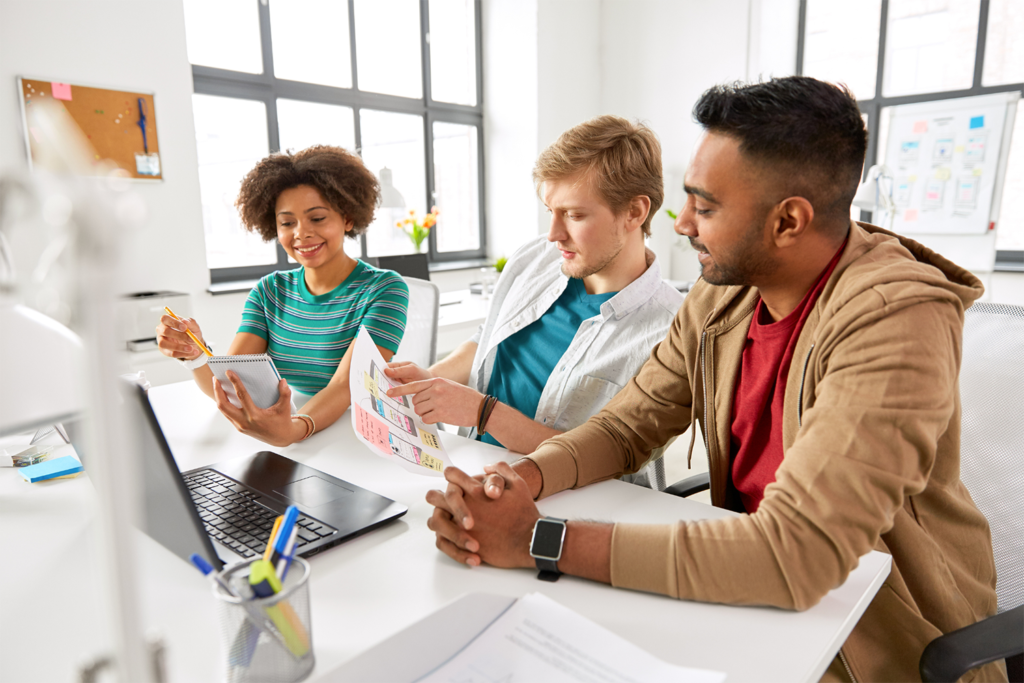 Three creative users working together on a laptop.