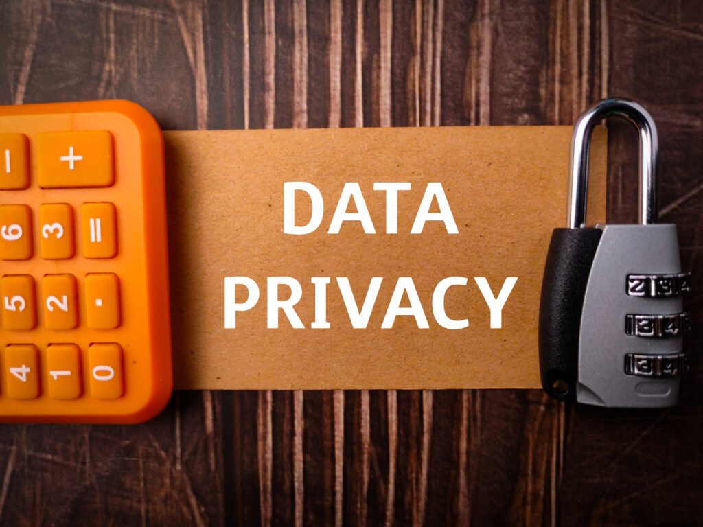 A calculator and a combination lock on a wooden surface, with a piece of paper in the center that reads "data privacy".
